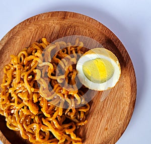 Fried noodles with boiled egg pieces on a wooden plate