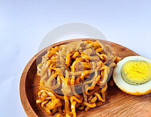 Fried noodles with boiled egg pieces on a wooden plate