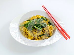 Fried noodles with red chopstick in white plate on white backgro
