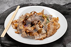 Fried noodles with vegetables and beef in white dish