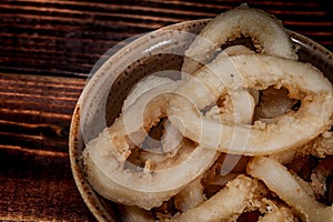 Fried onion rings. Paper envelope, wooden table. Close-up