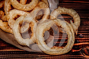 Fried onion rings. Paper envelope, wooden table. Close-up