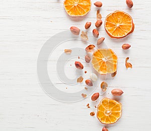 Fried peanut on a white wooden background. Dry slices of citrus.