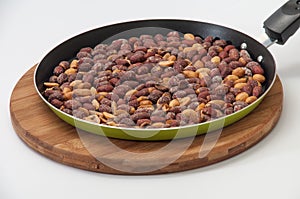 Fried peanuts in a pan on a kitchen wooden board