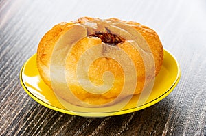 Fried pie with meat belyash in yellow saucer on wooden table
