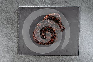 A fried piece of meat on a metal dark board, which is on a stone kitchen table
