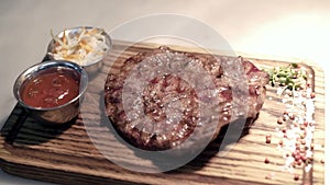 Fried piece of meat served on wooden tray. Action. Close-up of juicy piece of steak cooked by professional chef and