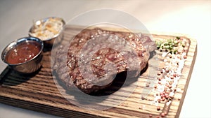 Fried piece of meat served on wooden tray. Action. Close-up of juicy piece of steak cooked by professional chef and