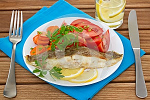 Fried plaice with lemon, salad and glass of water