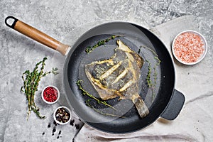 Fried plaice in a pan. Gray background, top view.