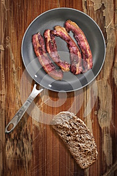 Fried Pork Ham Rashers In Teflon Frying Pan With Slice Of Integral Brown Bread Set On Old Cracked Wooden Picnic Table photo