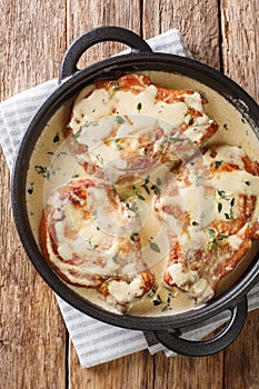 Fried pork chops stewed in a creamy wine sauce with thyme close-up in a pan. Vertical top view