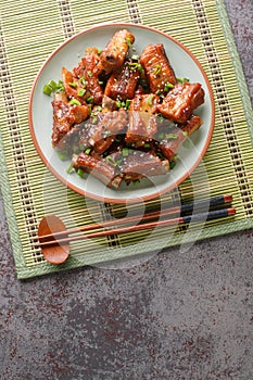 Fried pork short ribs in sweet and sour sauce in Asian style close-up in a plate. vertical top view