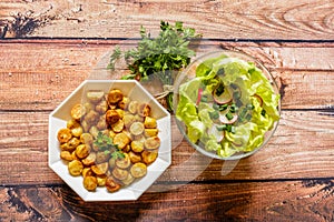 Fried potato balls with parsley and lettuce on wooden background