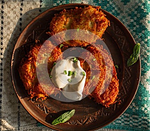 Fried potato pancakes on a clay brown plate, sour cream, green onions. food, potato pancakes, dish