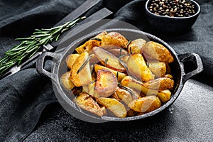 Fried potato wedges, French fries in a pan. Black background. Top view