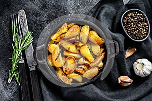 Fried potato wedges, French fries in a pan. Black background. Top view