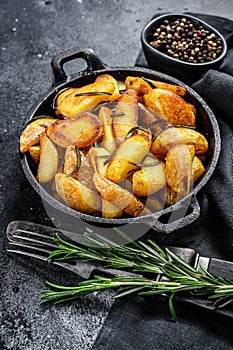 Fried potato wedges, French fries in a pan. Black background. Top view