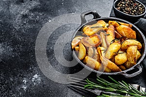Fried potato wedges, French fries in a pan. Black background. Top view. Copy space