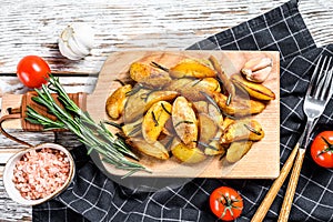 Fried potato wedges, French fries on a wooden cutting board. White background. Top view