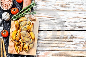 Fried potato wedges, French fries on a wooden cutting board. White background. Top view. Copy space