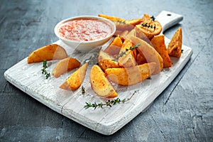 Fried potato wedges with hot salsa sauce, herbs on white board