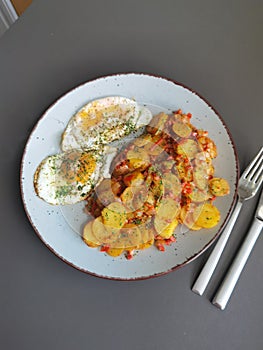 Fried potatoes with bacon cubes and fried eggs