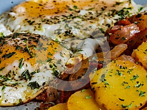Fried potatoes with bacon cubes and fried eggs
