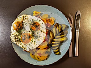 Fried potatoes with bacon cubes and fried eggs