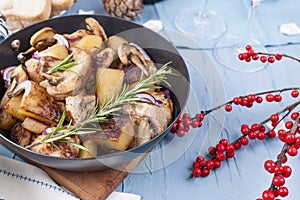 Fried potatoes in a black frying pan with a wooden handle on a b