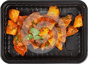 Fried potatoes in a disposable rectangular plastic black lunch box top view on a white background