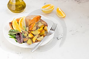 Fried potatoes with fish and green salad on a white plate