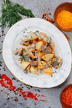 Fried potatoes with mushrooms and onion in iron pan at gray background. Thanksgiving dinner.