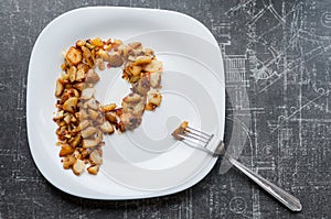 Fried potatoes in a plate on a black table with a fork