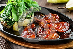 Fried prawns in a spicy sweet sauce with salad spinach and pineapple in a pan on wooden table. Healthy seafood, close up,