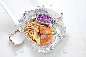 Fried rainbow trout fillet served with potato fries and salad, in takeaway boxes. Fish and chips, lunch set.