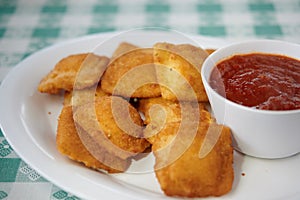 Fried ravioli on white plate with marinara sauce