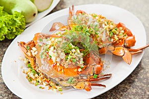 Fried red crab with onion, lettuce and herbs on white dish