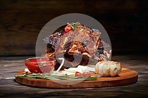 Fried ribs with rosemary, onion, sauce on a wooden round Board.