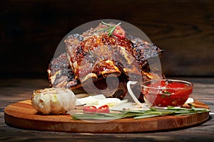 Fried ribs with rosemary, onion, sauce on a wooden round Board.