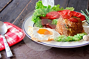 Fried rice with chinese sausage served in a white plate with fried egg, tomato and lettuce