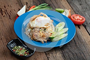 Fried rice with egg on top, pork crackling and cucumber