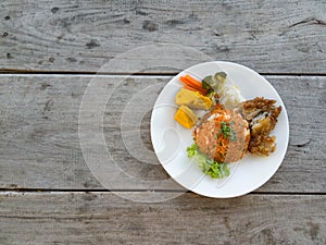 Fried rice, fried chicken  vegetables on a wooden table