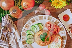 Fried Rice with Fried Egg Put on the wooden table and the tomatoes, cucumbers, garlic, shallots.