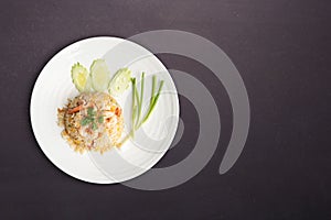 Fried rice with shrimp in round white dish isolated on black nature stone background. Thai Food concept