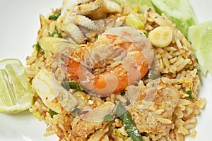 Fried rice shrimp and squid with pork in tom yum sauce topping slice cucumber couple lemon on plate