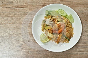 Fried rice shrimp and squid with pork in tom yum sauce topping slice cucumber couple lemon on plate