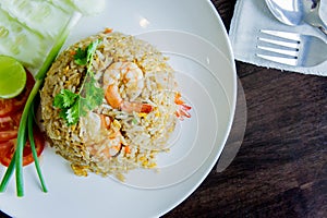 Fried rice with shrimp in a white dish on wood table in thai foo