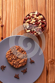 Fried Roasted peanut seed in clay bowl and chocolate cookies on plate. top view