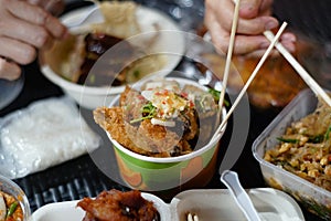 Fried roe fish in seafood dipping sauce in a paper bowl on a black rattan table. photo